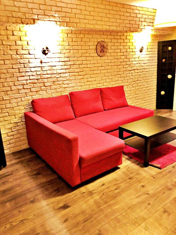 ein rotes Sofa im Wohnzimmer mit Ziegelwand in der Unterkunft Dream Residence nerva traian! in Bukarest