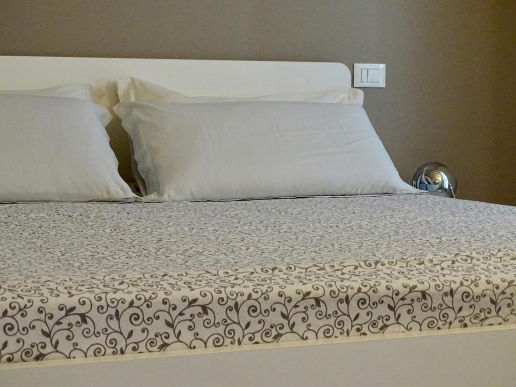 un letto con lenzuola e cuscini bianchi di Accademia 35 a Mantova