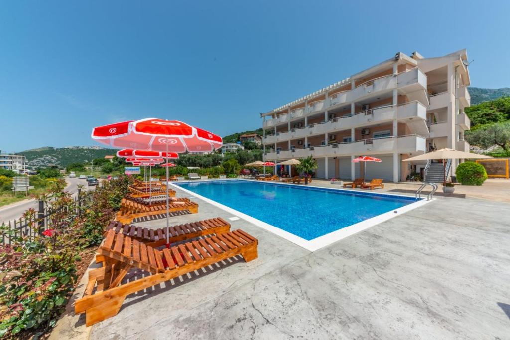 a hotel with a swimming pool with chairs and an umbrella at Apartmani Djurovic in Dobra Voda