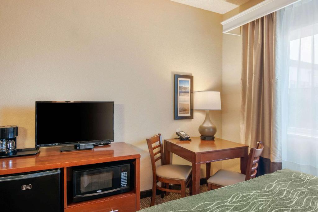 a hotel room with a bed and a desk with a television at Comfort Inn Medford North in Medford