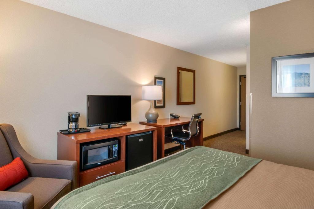 a hotel room with a bed a desk and a tv at Comfort Inn Medford North in Medford