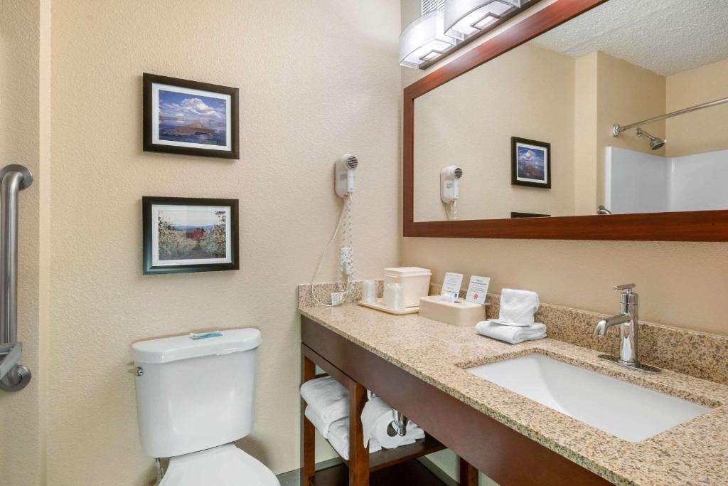 a bathroom with a toilet and a sink and a mirror at Comfort Inn Medford North in Medford