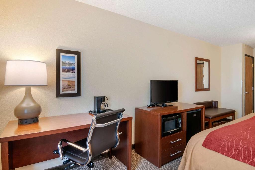 a hotel room with a desk with a computer and a bed at Comfort Inn Medford North in Medford