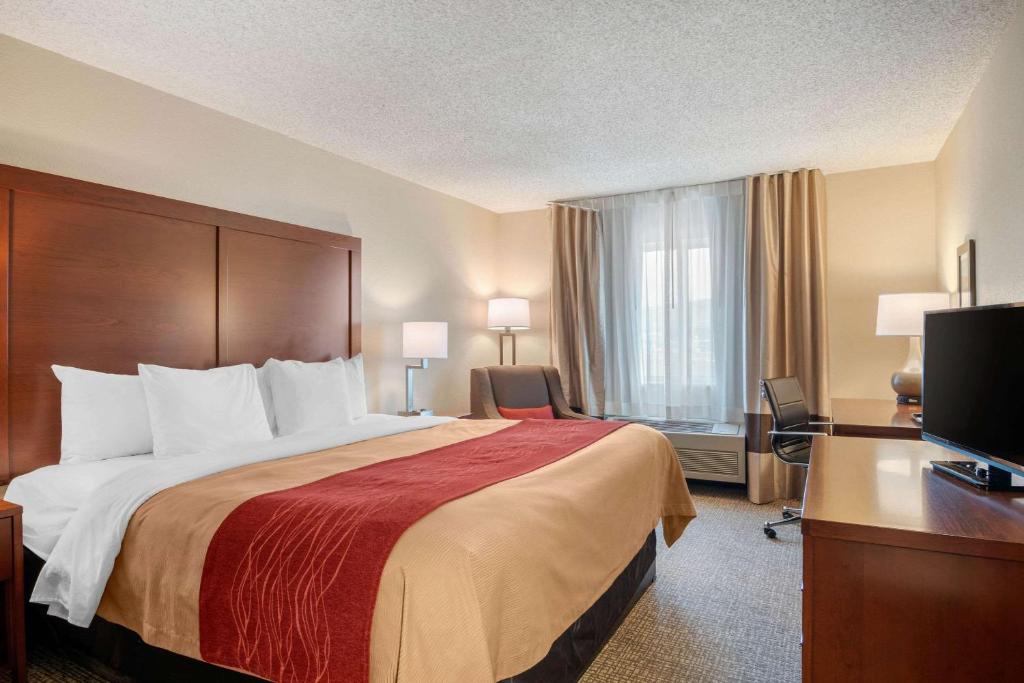 a hotel room with a bed and a desk and a television at Comfort Inn Medford North in Medford