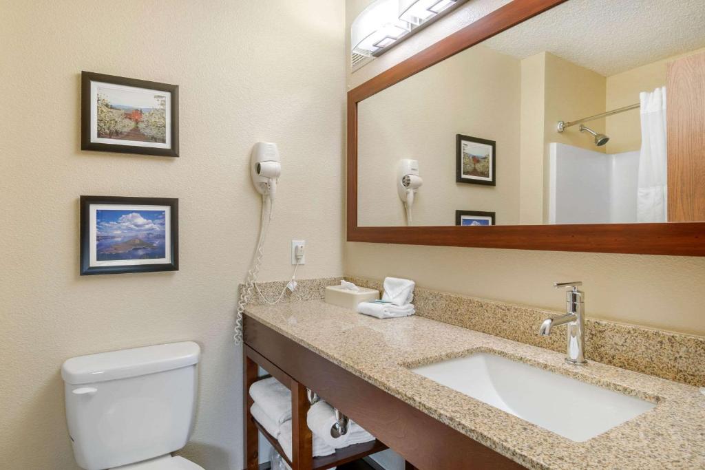 a bathroom with a toilet and a sink and a mirror at Comfort Inn Medford North in Medford