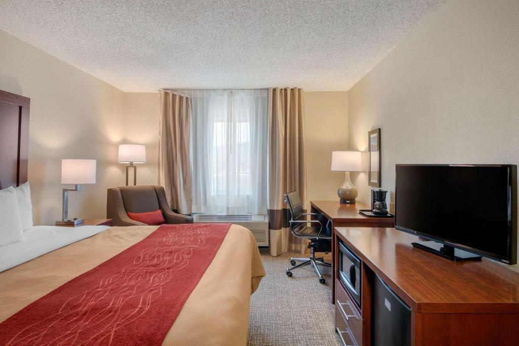 a hotel room with a bed and a flat screen tv at Comfort Inn Medford North in Medford