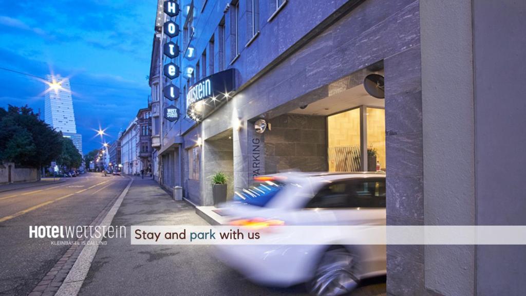 a white car driving down a street next to a building at Hotel Wettstein in Basel