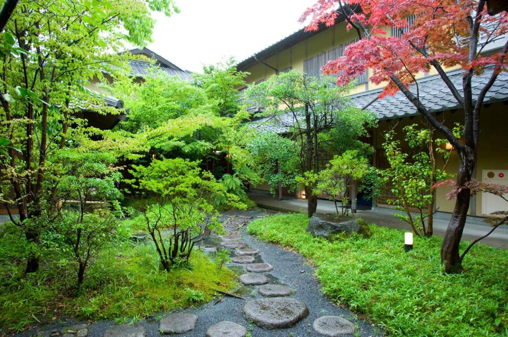a garden with rocks and trees in front of a building at Yufuin Santoukan in Yufuin