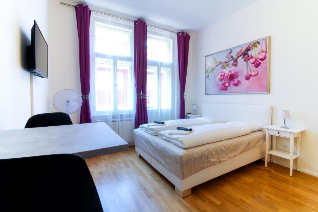 a bedroom with a bed and a window with purple curtains at Bouquet Apartments in Prague