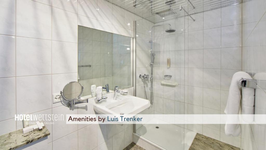 a white bathroom with a sink and a mirror at Hotel Wettstein in Basel
