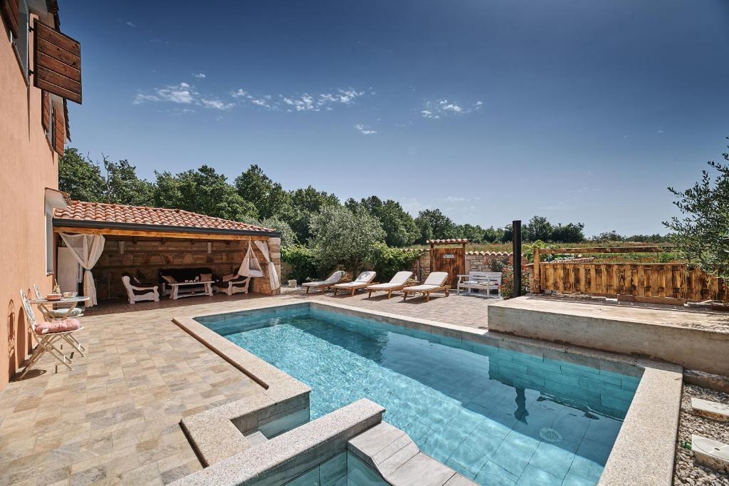 una piscina en un patio con sillas y una casa en Villa Amelie, en Kaštelir