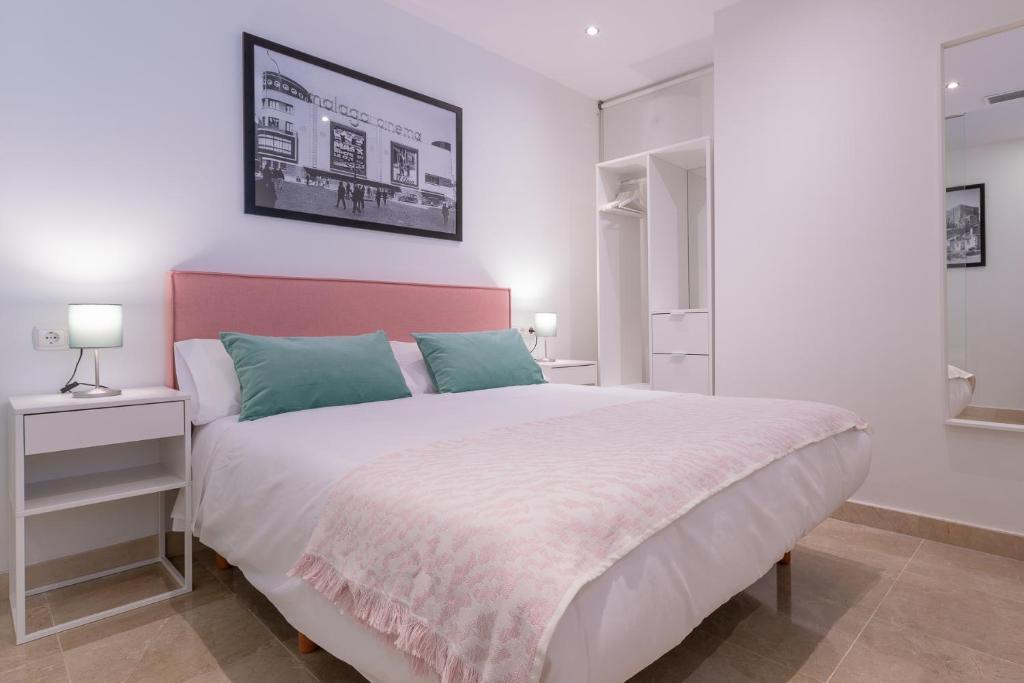 una camera da letto con un grande letto bianco con testiera rosa di Apartamentos Miraflores a Málaga