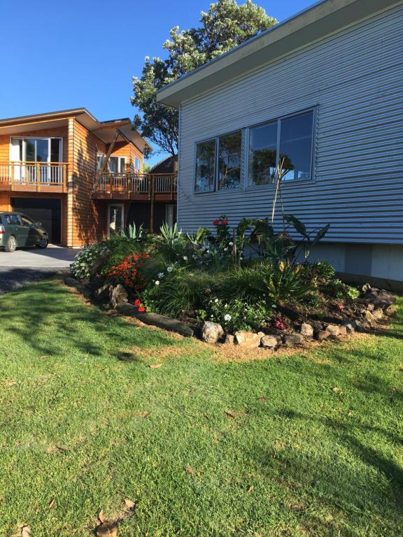 a house with a landscaping in front of a yard at Chalet Cullen, in Mangawhai