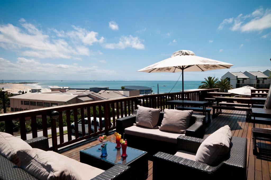 a balcony with couches and an umbrella and the beach at The Kelway Hotel in Port Elizabeth