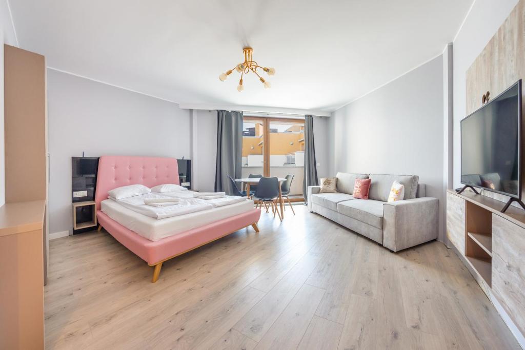 uma sala de estar com uma cama rosa e um sofá em Prywatne apartamenty Sun & Snow w Maloves em Władysławowo