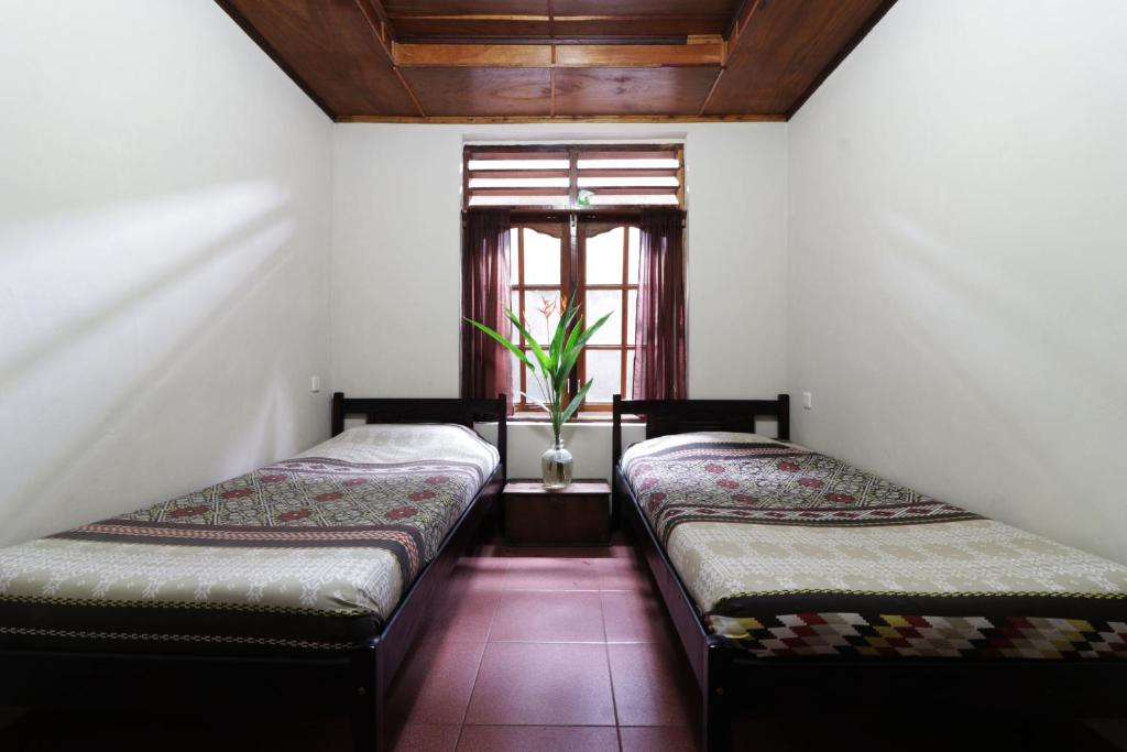 two beds in a room with a window at Bagus Bay Homestay in Tuktuk Siadong