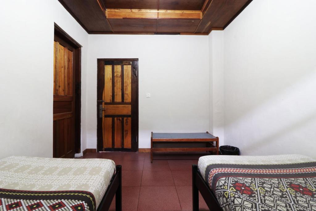 a room with two beds and a wooden door at Bagus Bay Homestay in Tuktuk Siadong