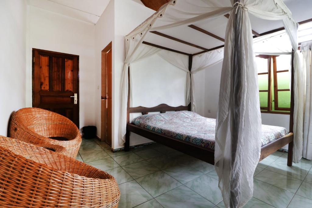 a bedroom with a canopy bed and a chair at Bagus Bay Homestay in Tuktuk Siadong