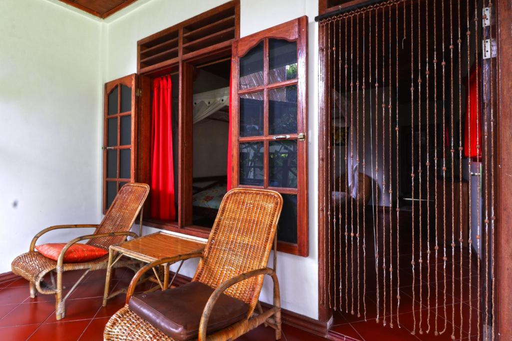 two chairs and a table in a room with a window at Bagus Bay Homestay in Tuktuk Siadong