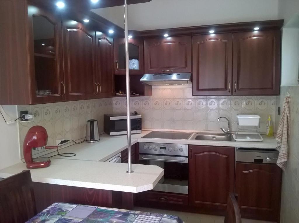 a kitchen with wooden cabinets and a stove top oven at ZENITH APARTMAN in Gárdony