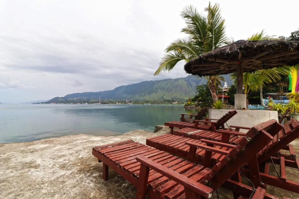 un grupo de bancos sentados en la playa cerca del agua en Bagus Bay Homestay, en Tuk Tuk