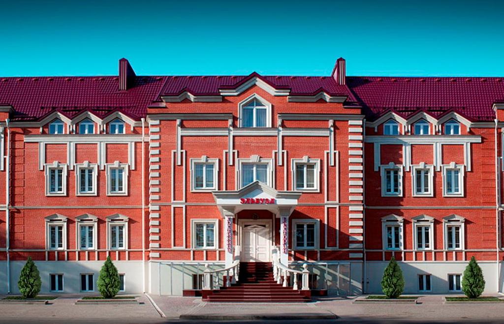 ein großes rotes Gebäude mit rotem Dach in der Unterkunft Hotel Elbuzd in Rostow am Don