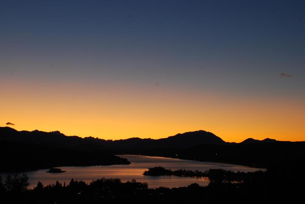 un tramonto su un lago con montagne sullo sfondo di Urlaub für Mensch und Tier - Appartements Pirkhof a Pörtschach am Wörthersee