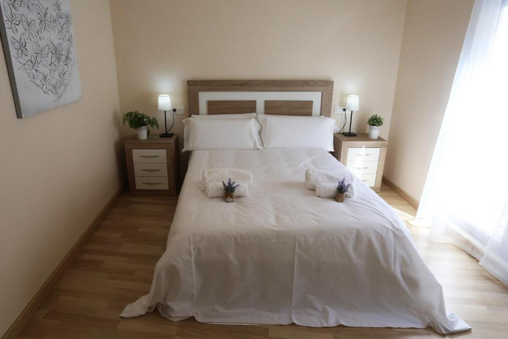 Un dormitorio con una cama blanca con dos flores. en Apartamento Puente Romano P1-1B, en Salamanca