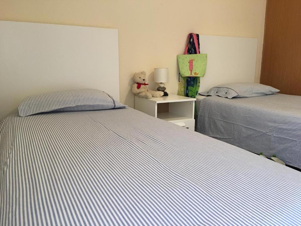 a bedroom with two beds and a teddy bear on a night stand at Apartamentos 7 Valles Jaca Centro in Jaca