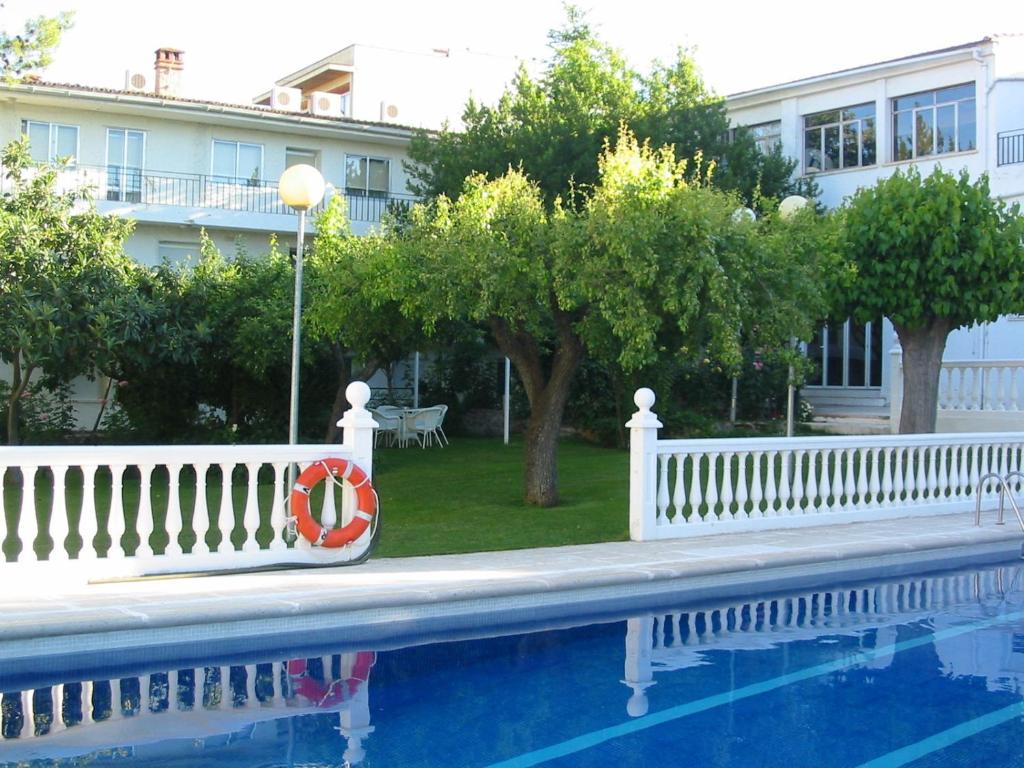 a white fence next to a swimming pool with a red life preserver at Hotel Rural Mariblanca in Sacedón