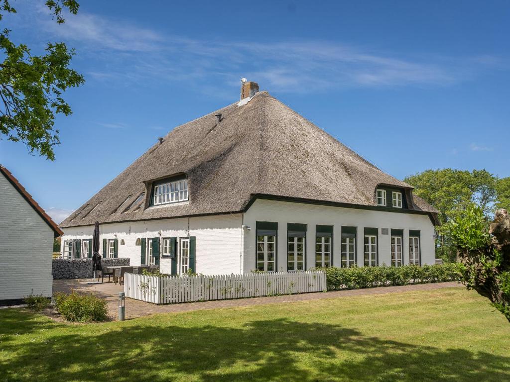 une maison avec un toit de chaume et une cour dans l'établissement Apartment in a sunny location in a farmhouse in De Cocksdorp on the island of Texel, à De Cocksdorp