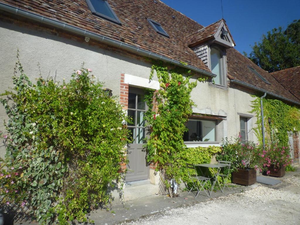 a cottage with a white door and some plants at Chambres d'Hôtes Les Potiers in Sens-Beaujeu