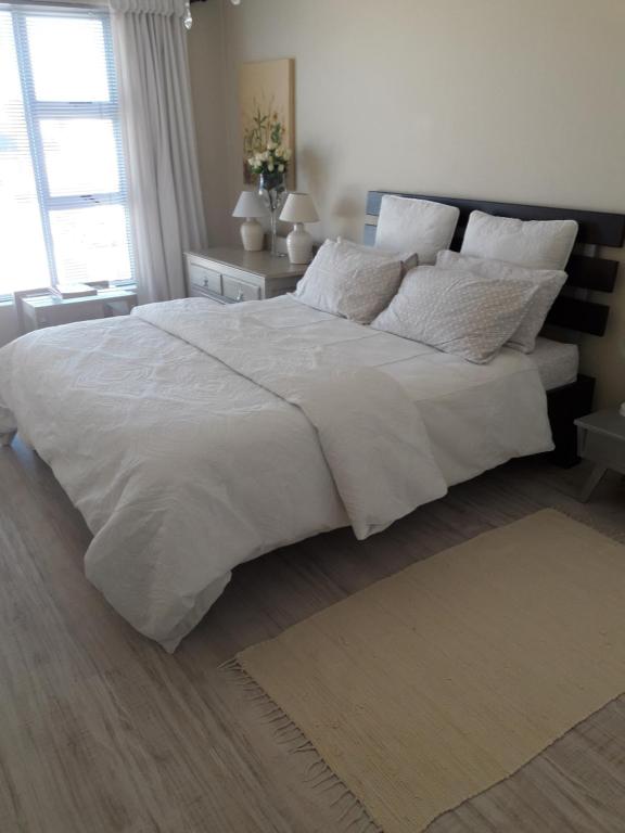 a bedroom with a large bed with white sheets and pillows at Joans place in Velddrif