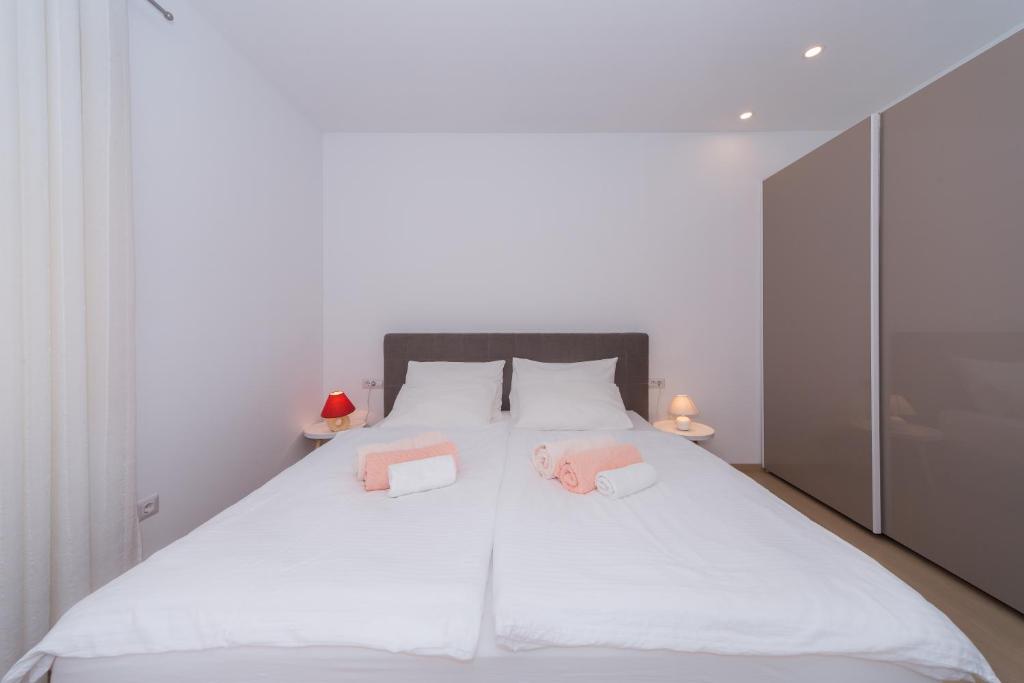 a bedroom with a large white bed with two pink pillows at A&J deluxe apartment in Biograd na Moru
