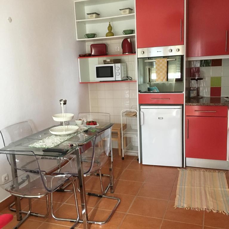 a kitchen with a glass table and red cabinets at Studio do Brejo - de 2 a 3 pessoas in Vila Nova de Milfontes