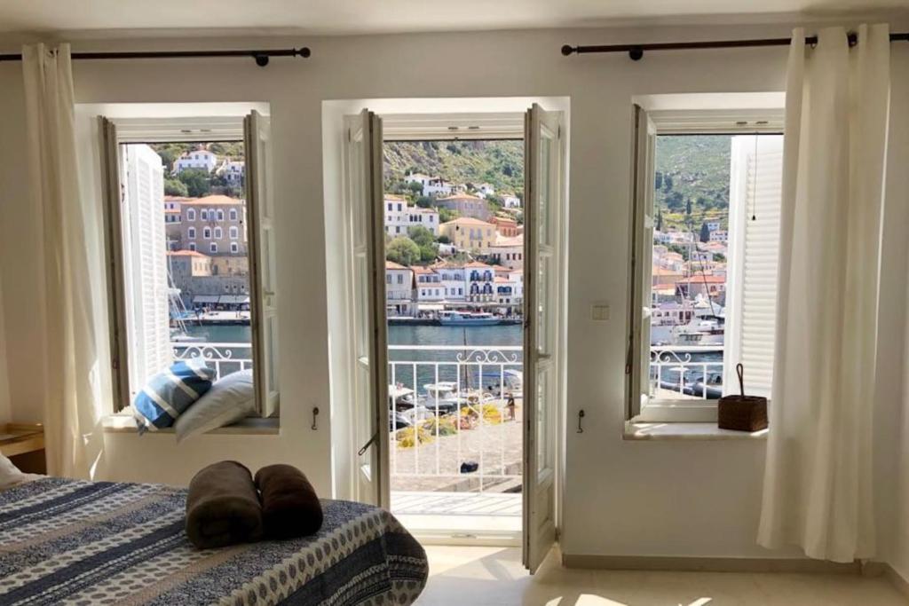 a bedroom with two windows and a bed with a view at Hydra's View in Hydra