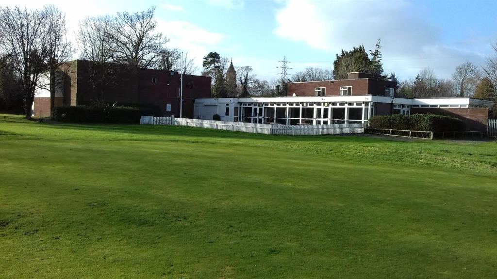 un bâtiment avec un champ vert devant lui dans l'établissement Hooton Golf Club, à Little Sutton