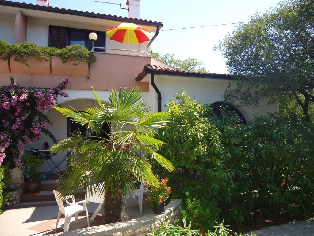 une maison avec un palmier et un parasol coloré dans l'établissement Apartments Barbara, à Pinezići