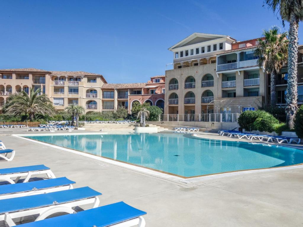 une grande piscine avec des chaises longues en face d'un bâtiment dans l'établissement Apartment Les Rivages de Coudoulière-31 by Interhome, à Six-Fours-les-Plages