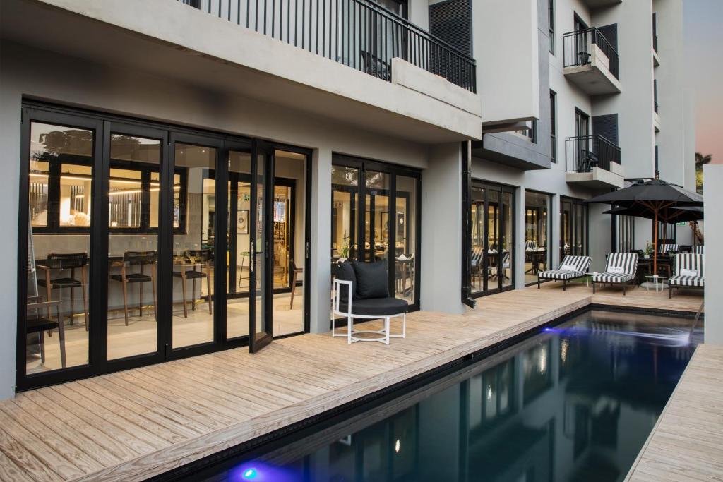 una piscina con una silla junto a un edificio en The Capital Melrose en Johannesburgo