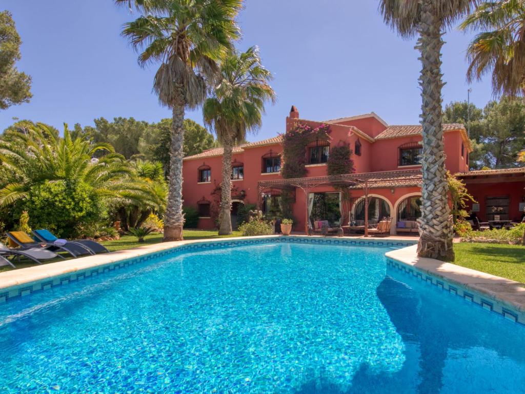 a swimming pool in front of a house with palm trees at Villa Villa Adelfa by Interhome in Jávea
