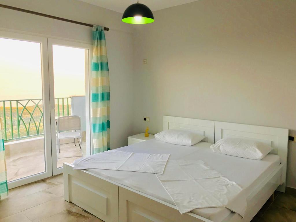 uma cama branca num quarto com uma varanda em Vila Milo em Vuno