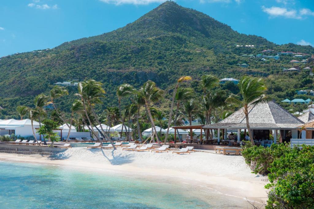 a beach with lounge chairs and a mountain in the background at Le Sereno in Gustavia