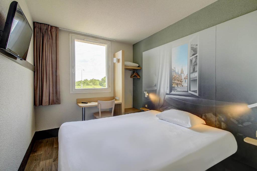 a large white bed in a room with a window at B&B HOTEL BEAUNE Nord in Savigny-lès-Beaune