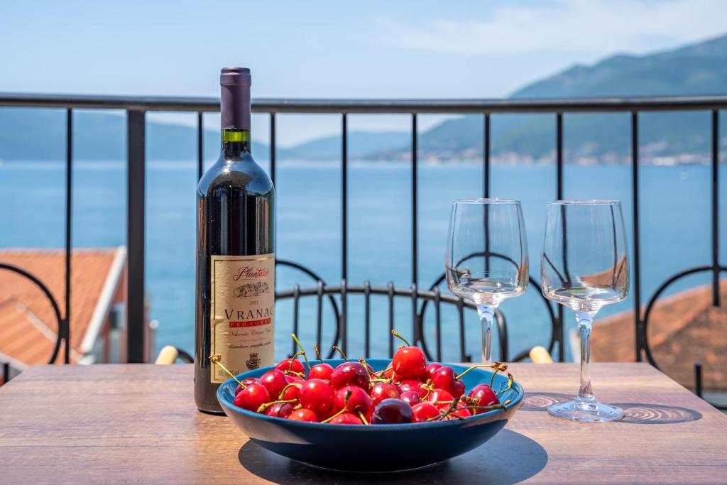 a bottle of wine and a bowl of fruit on a table with glasses at Sealine Apartments A2 in Tivat