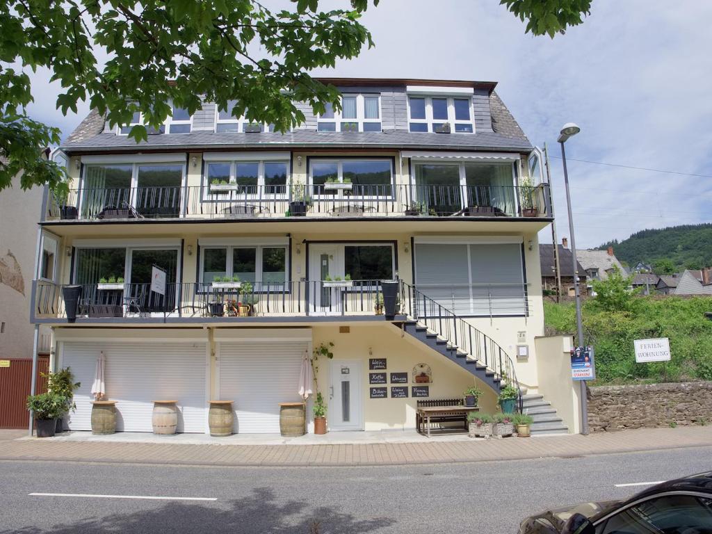 ein großes weißes Haus mit einem Balkon und einer Treppe in der Unterkunft Appartements Moselblick in Klotten