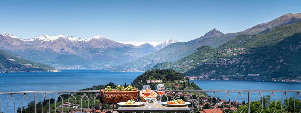 una mesa con copas de vino y comida en un balcón con vistas al lago en Hotel Il Perlo, en Bellagio