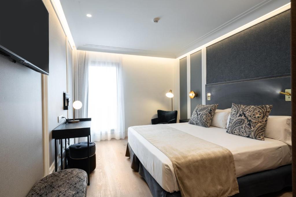 バルセロナにあるカタロニア プラザ カタルーニャのベッドと机があるホテルの部屋