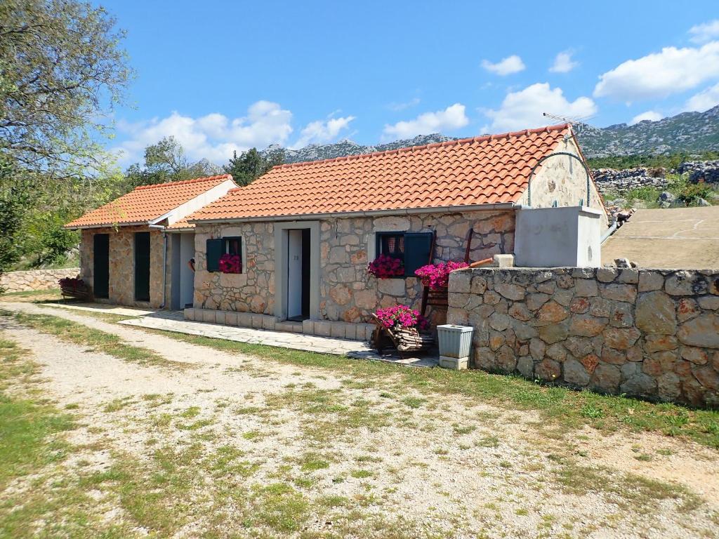 a small stone house with a stone wall at Holiday Home Jukići in Seline