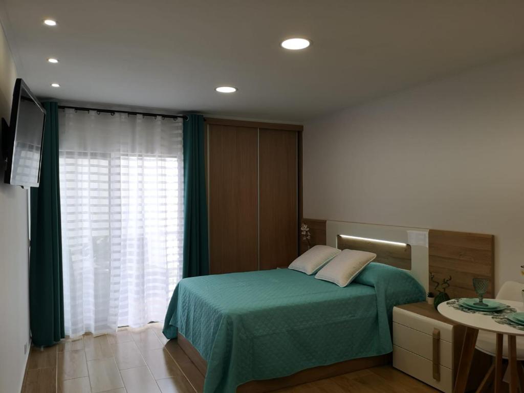 ein Schlafzimmer mit einem Bett mit einer grünen Decke und einem Fenster in der Unterkunft Lux Home in Albufeira